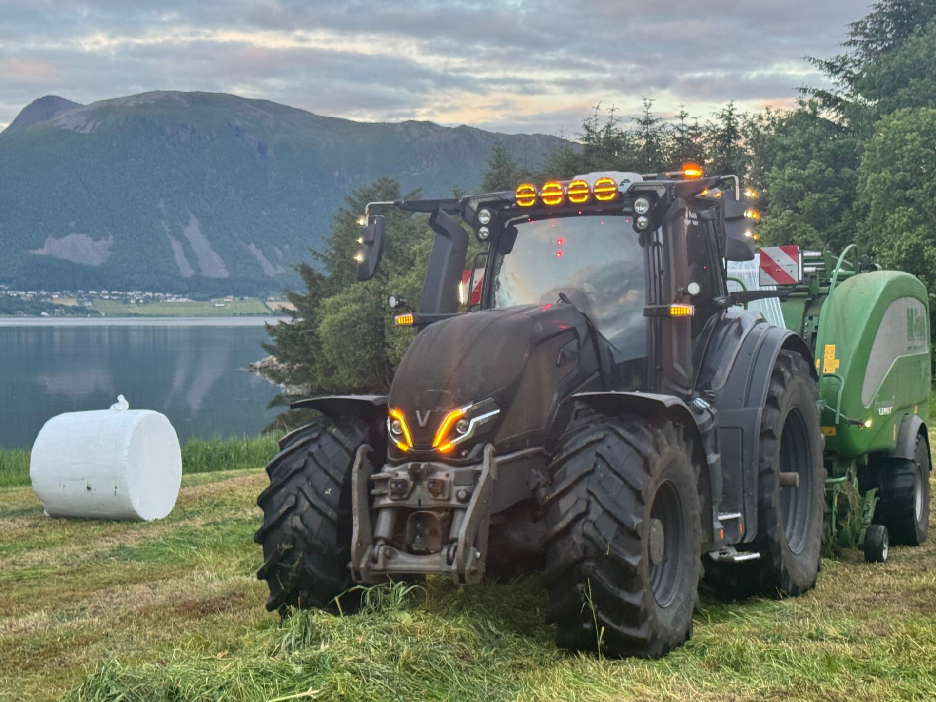 Valtra-traktor med rundballepresse foran fjorden i Hustadvika